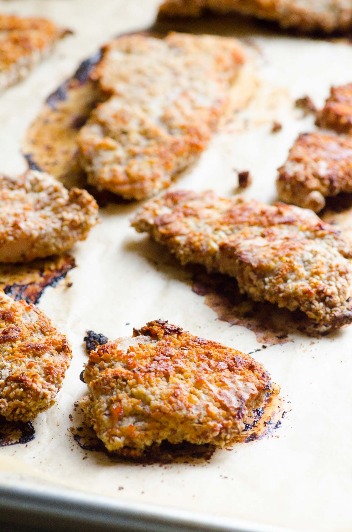 Baked almond crusted chicken tenders on baking sheet.