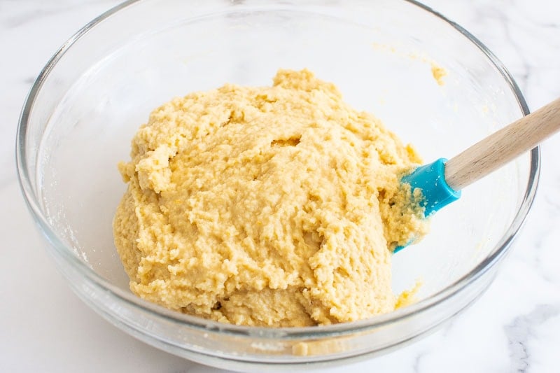 Almond flour muffin batter being stirred together with a blue spatula.