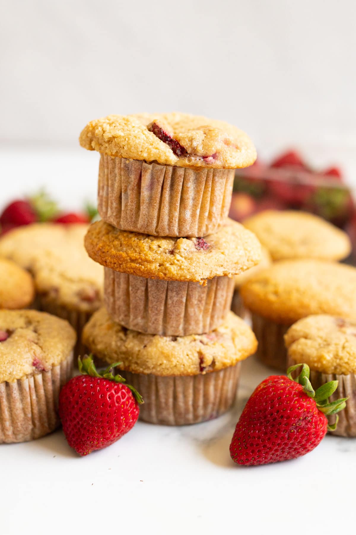 Three almond flour strawberry muffins stacked on top of each other.