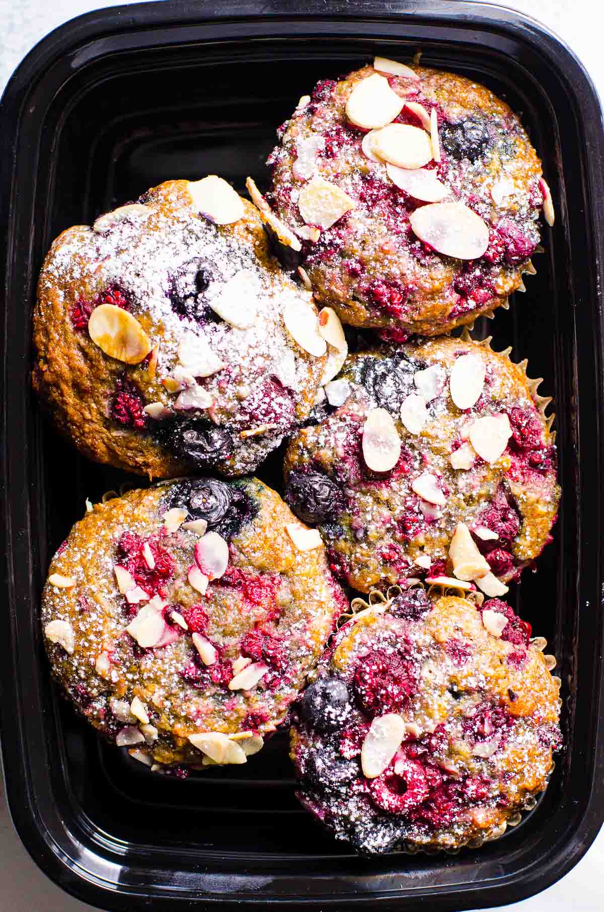 Healthy almond muffins in a black storage container.