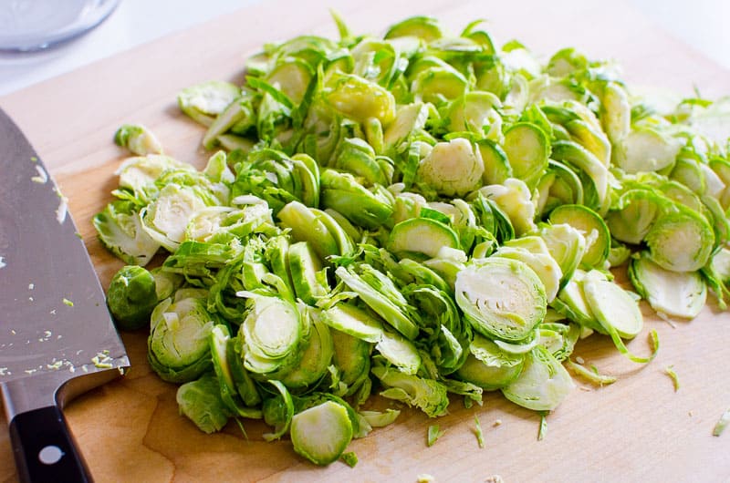 Thinly sliced brussels sprouts on cutting board.