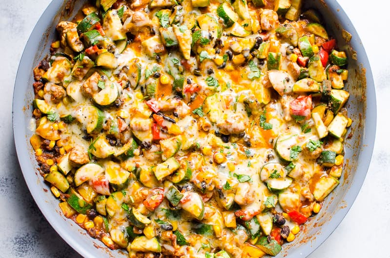 Tex-Mex chicken and zucchini with melted cheese on top and served in a large skillet.