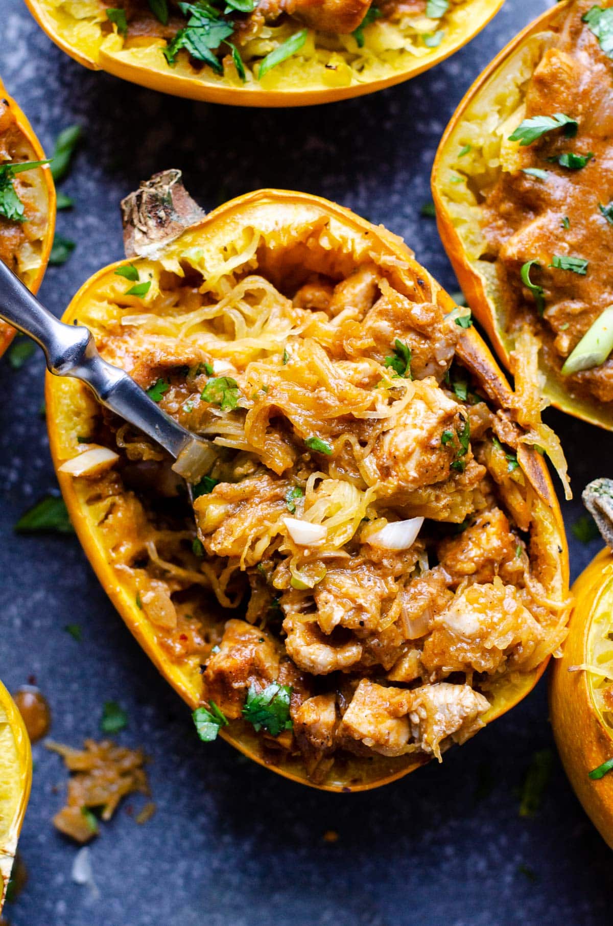 Butter chicken spaghetti squash on a fork inside the squash shell.
