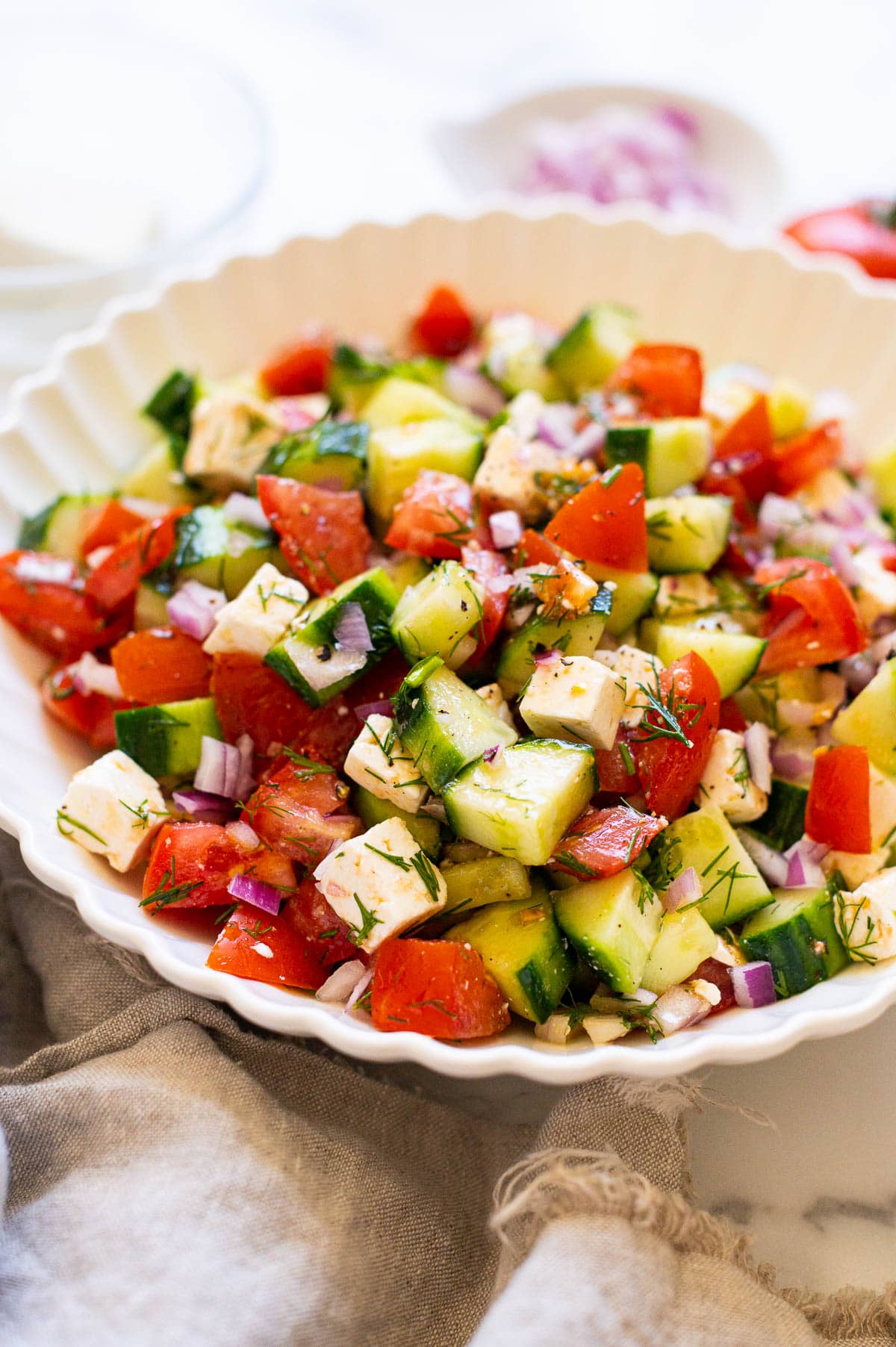 Side view of tomato cucumber salad in a bowl.