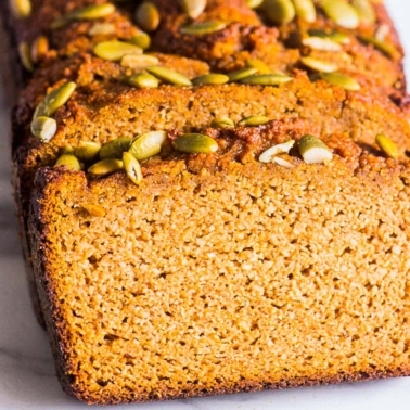 Almond flour pumpkin bread sliced and topped with pumpkin seeds.
