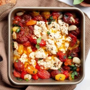 Baked feta dip with tomatoes, garlic and basil in square baking dish.