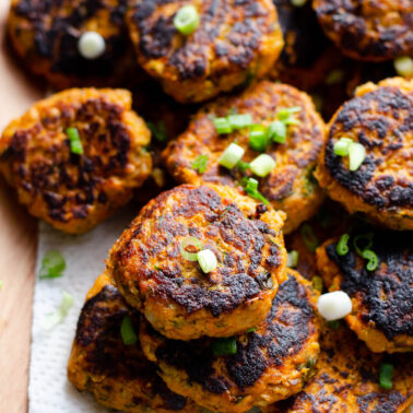 Canned salmon cakes garnished with green onion and served on a platter.