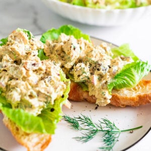 Curry chicken salad served on a croissant with lettuce on a plate.