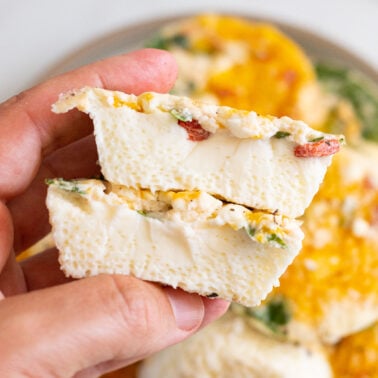 Person holding egg white bites cut in half to show the texture.