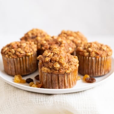 Six healthy carrot muffins on white plate.
