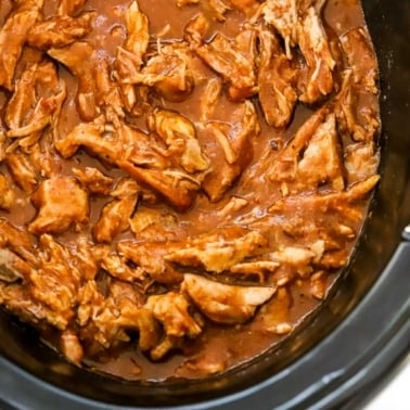 Pulled pork with BBQ sauce in black slow cooker.
