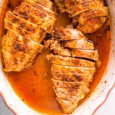 Sliced baked chicken breast in white dish.