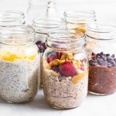 Healthy overnight oats with yogurt, chia seeds and toppings in mason jars.
