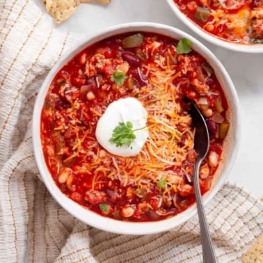Healthy turkey chili with sour cream, cheese and cilantro in a bowl.
