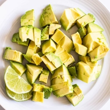 cut up avocado on plate with lime