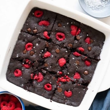 Oat flour brownies with raspberries in white baking dish.