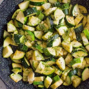 Sauteed zucchini in skillet garnished with dill.
