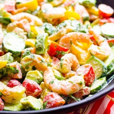 Closeup shrimp avocado salad with tomatoes, peppers and creamy yogurt dressing.
