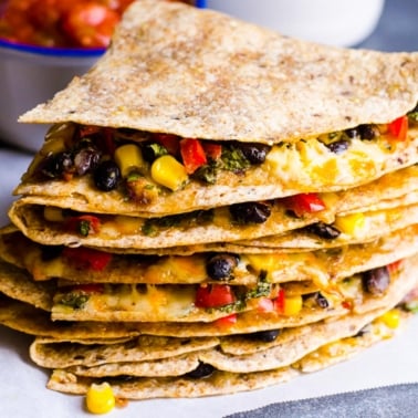A stack of vegetarian quesadillas showing corn, black beans and melted cheese.