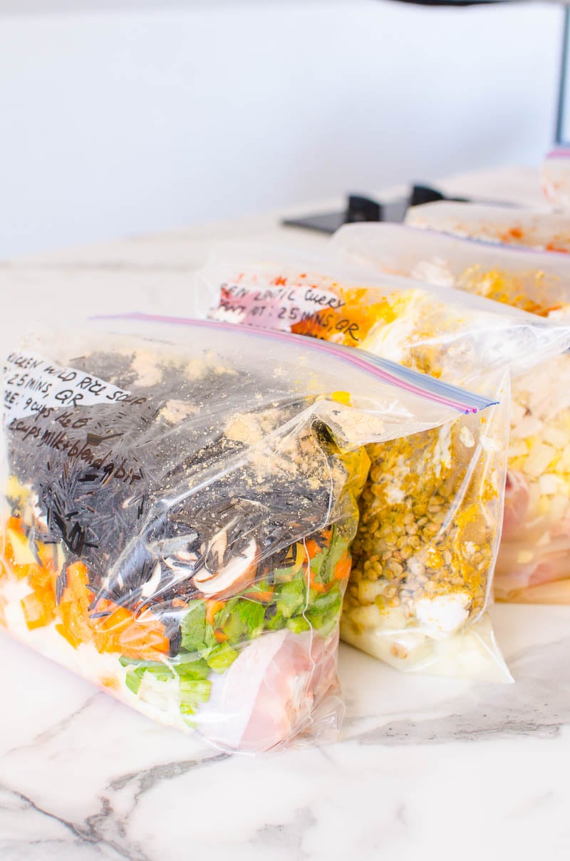 Four healthy freezer meals in storage bags sealed and placed on a counter.