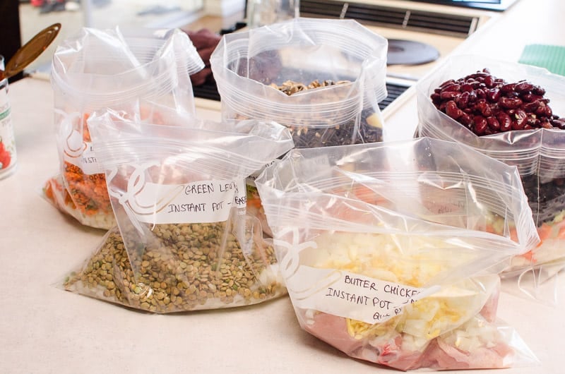 Five bags with healthy freezer meals on a kitchen counter.