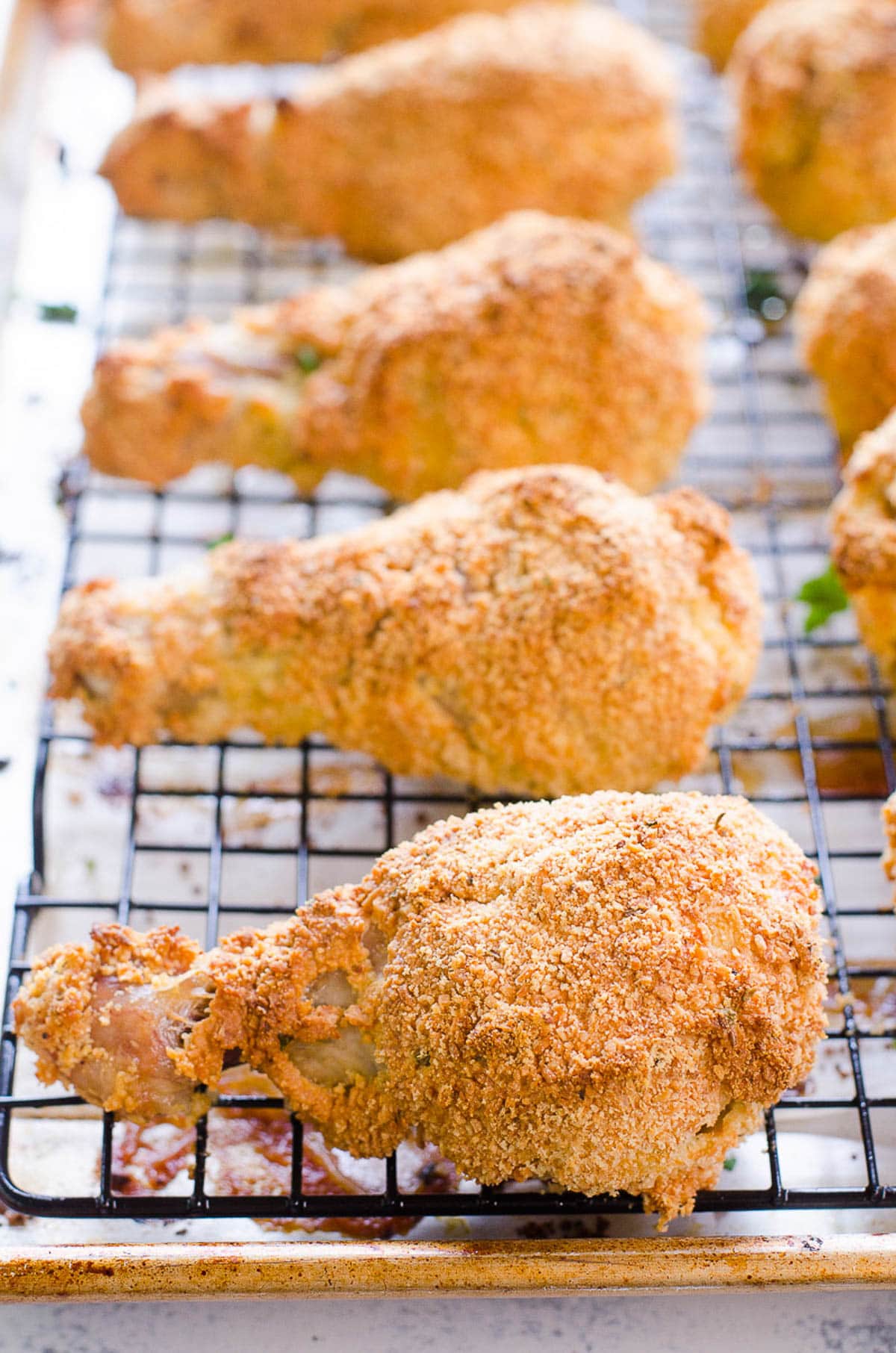 Healthy fried chicken drumsticks on a wire rack.