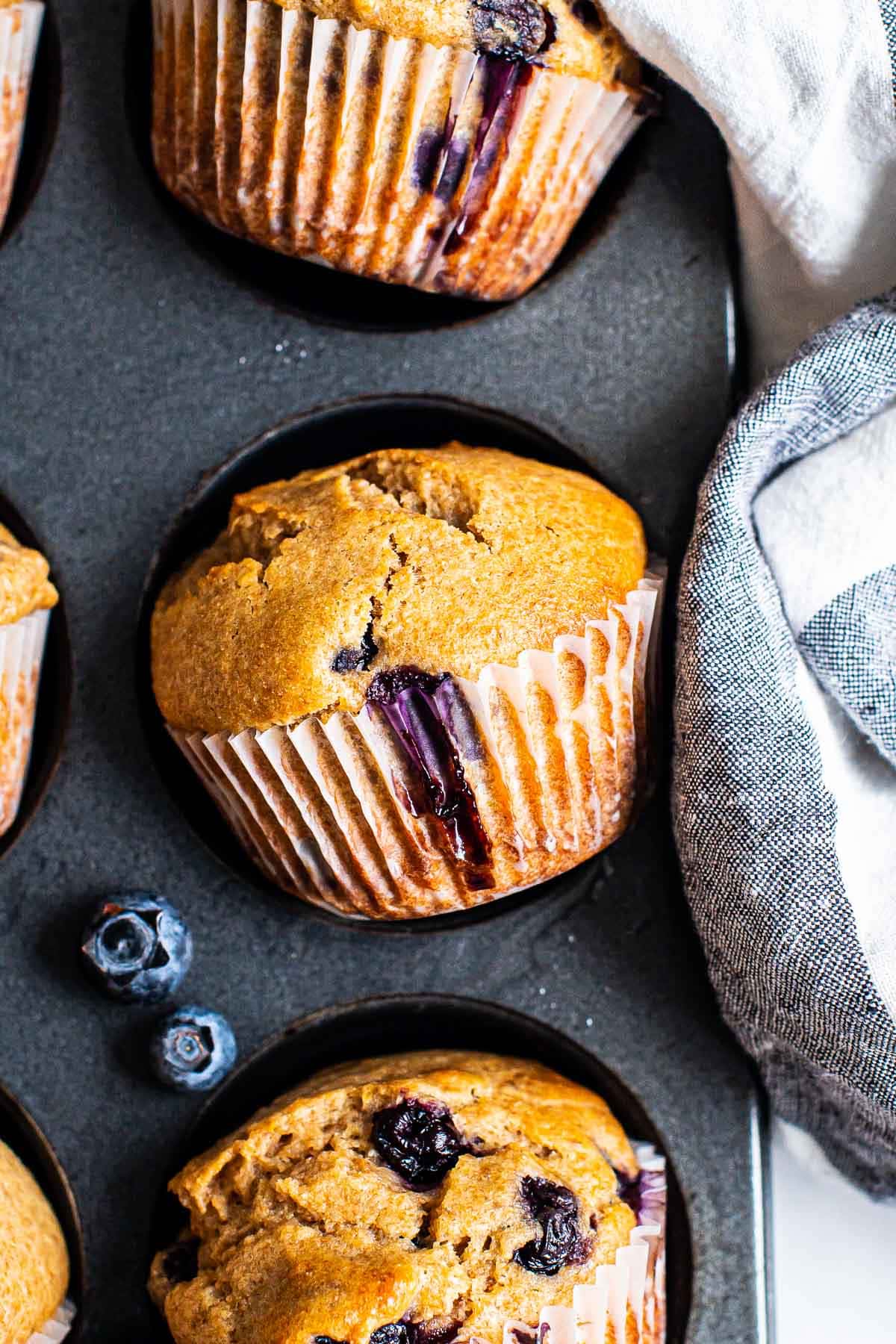 Lemon blueberry muffins in a wrapper in a muffin tin.