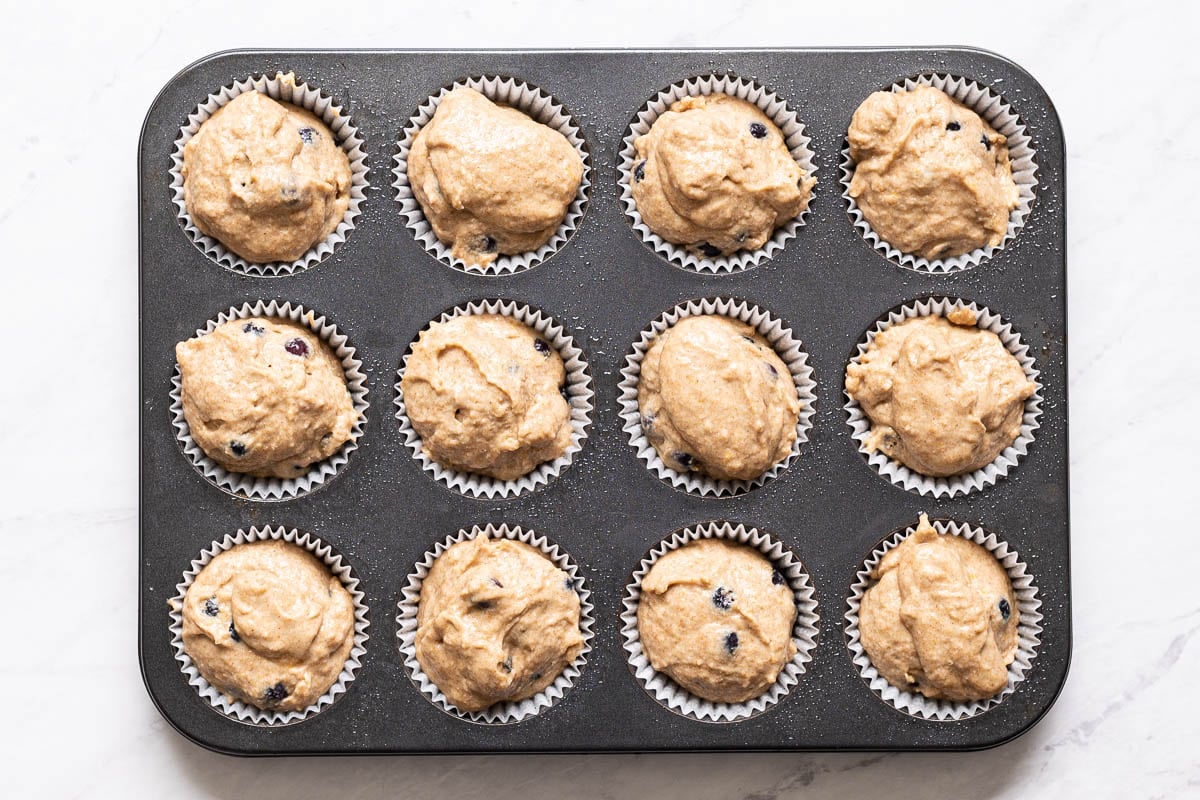 Raw muffin batter in a gray muffin tin.