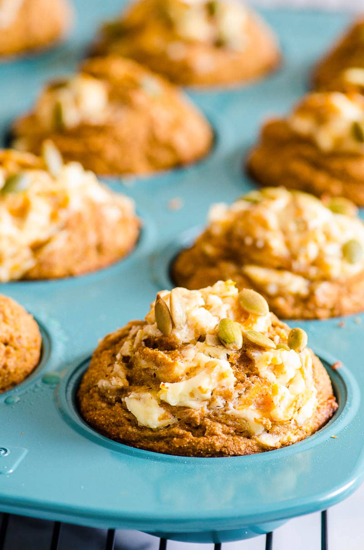 Healthy Pumpkin muffins with cream cheese and pumpkin seeds on top.