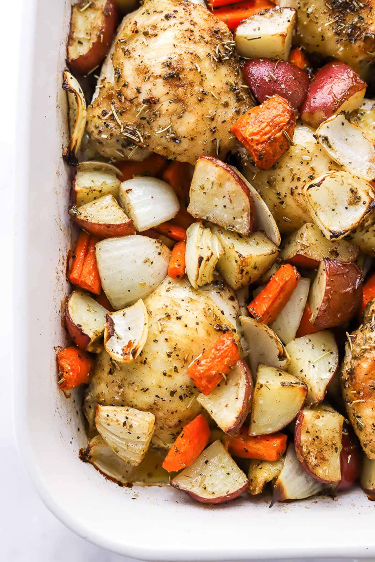 Roasted chicken thighs and potatoes in baking dish.
