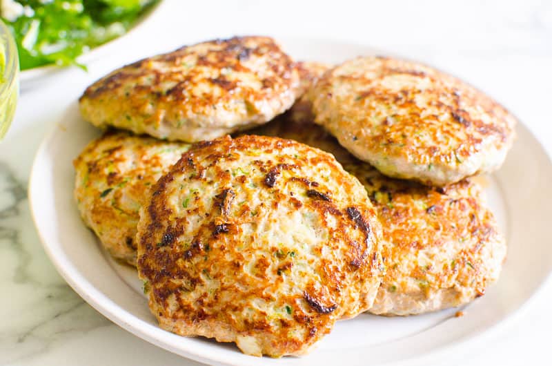 Turkey burger patties with zucchini on a plate.