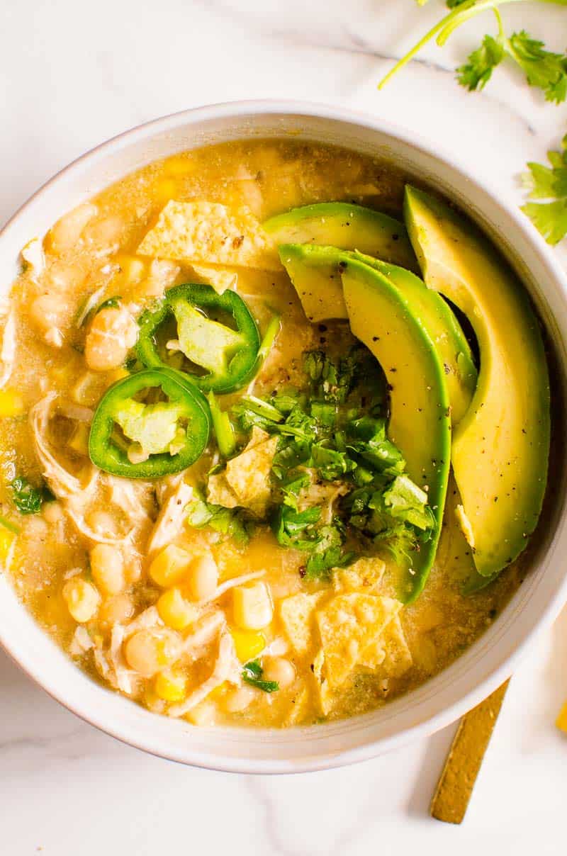 Healthy white chicken chili served with avocado slices, cilantro and jalapenos.