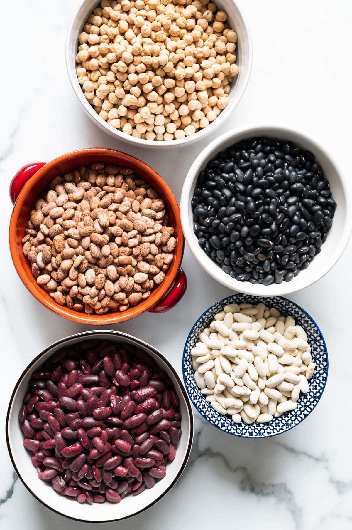Five bowls with various dried beans.
