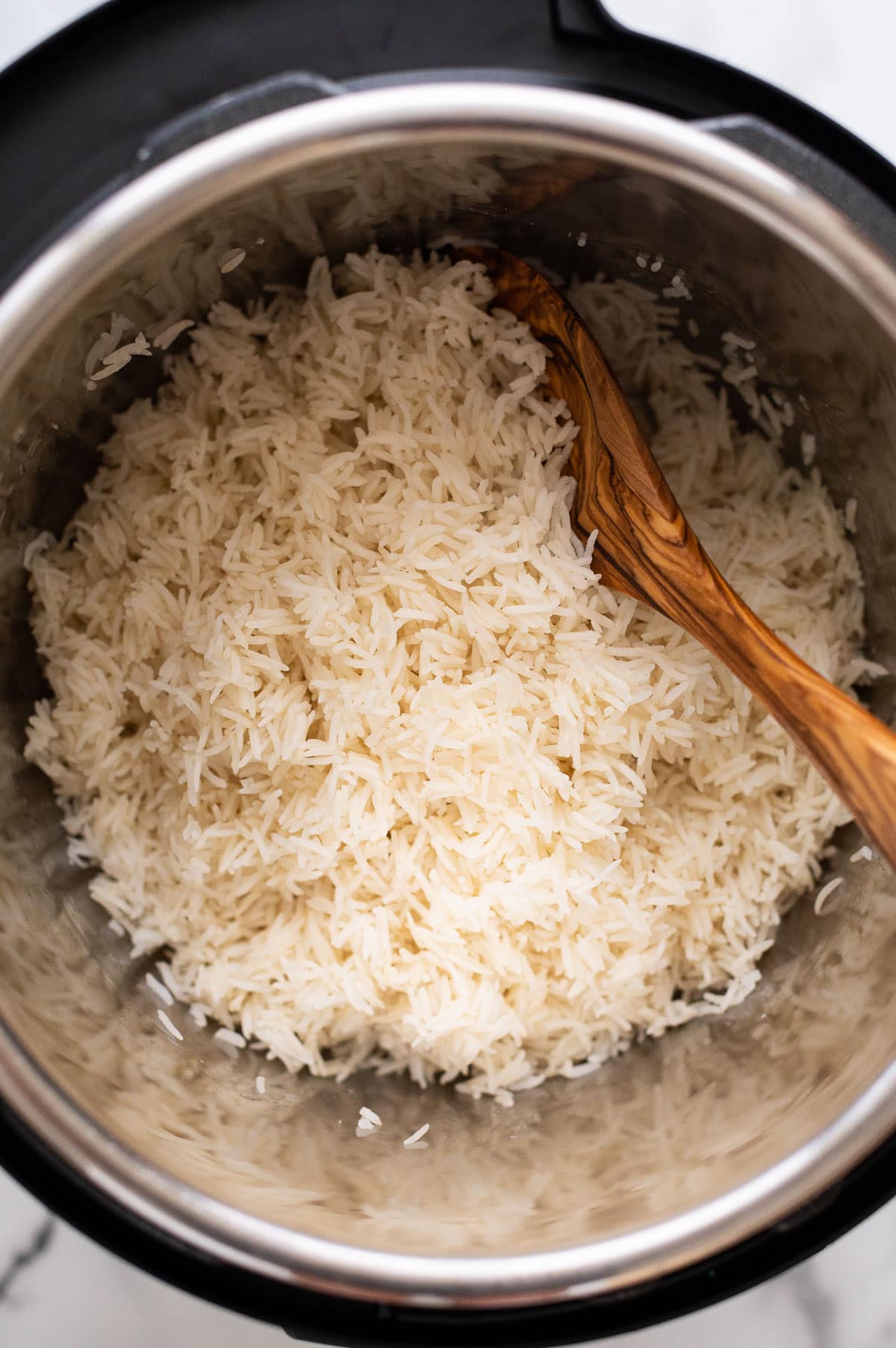Basmati rice in instant pot with wooden spoon.