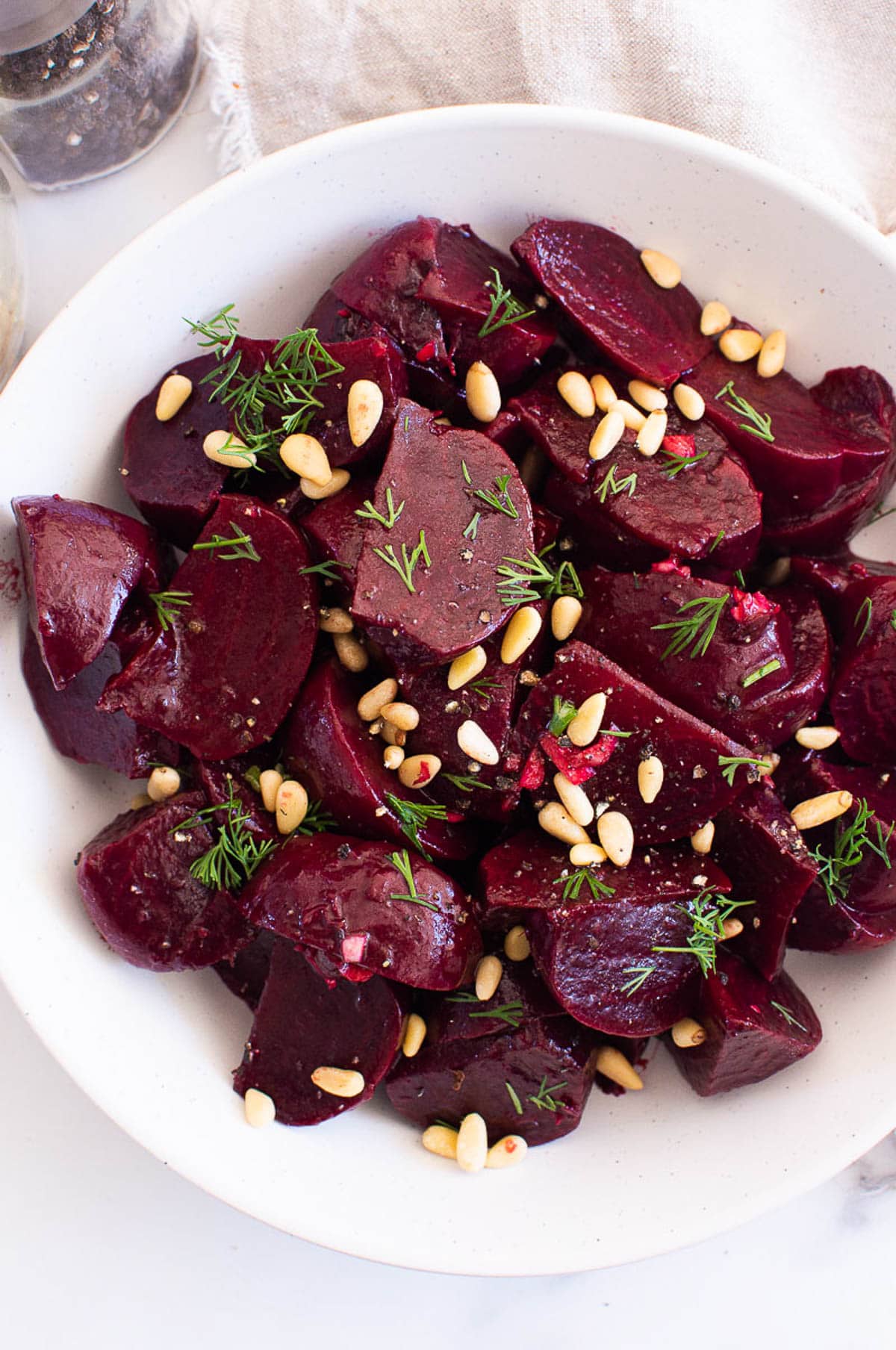 Cooked instant pot beets with pine nuts and dill served in a bowl.