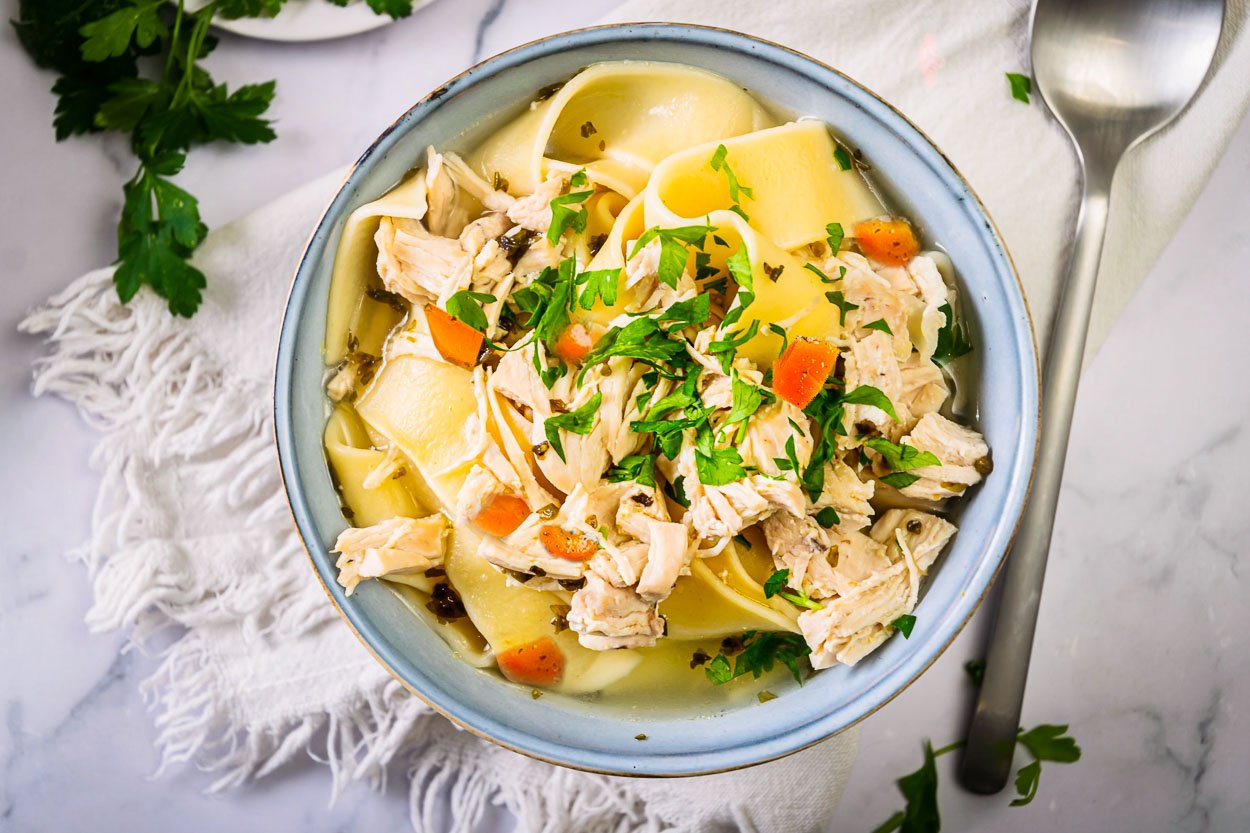 Instant pot chicken noodle soup with carrots and parsley garnish.