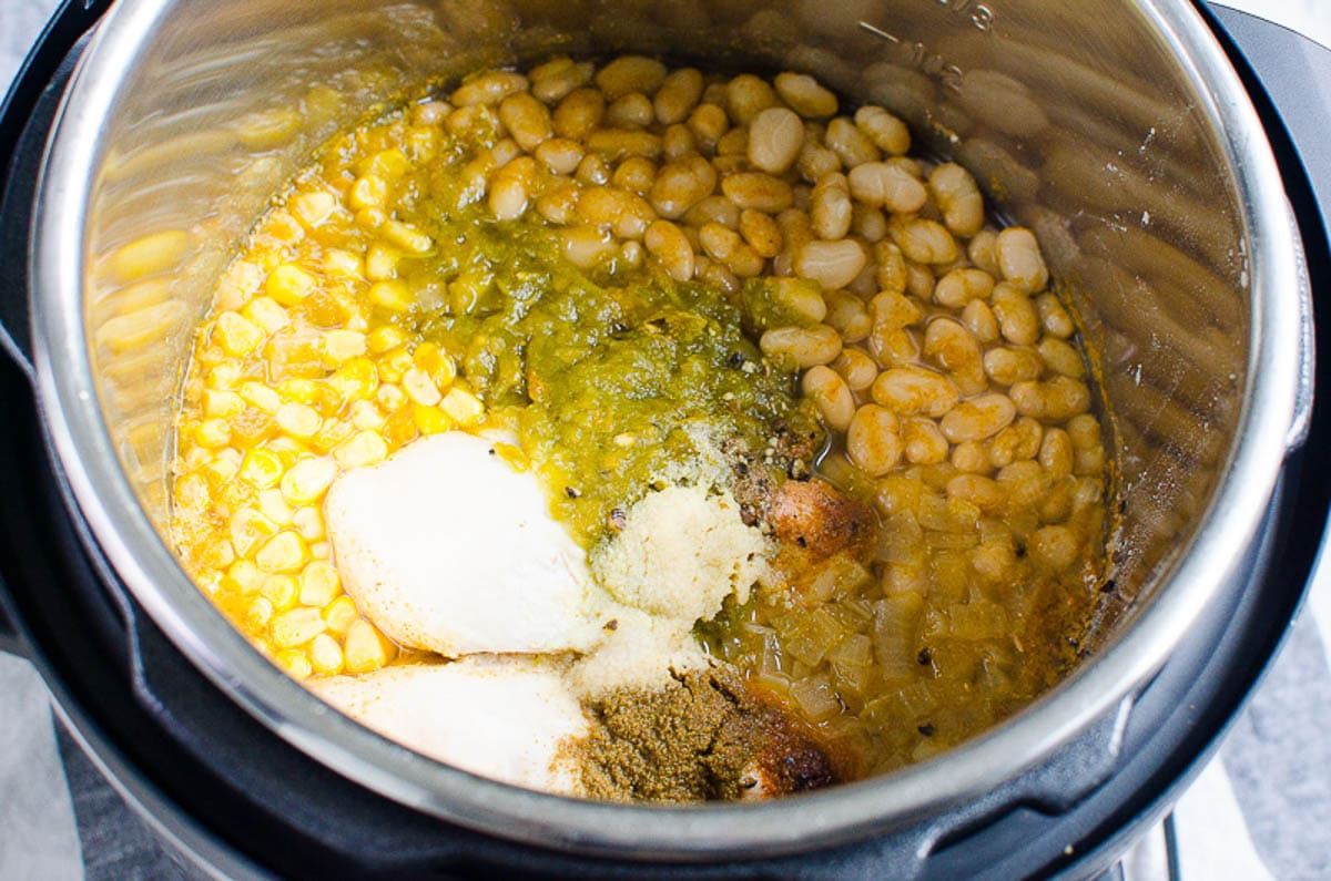 Chicken breasts, beans, corn, green chilis, onion and seasonings in Instant Pot liner.