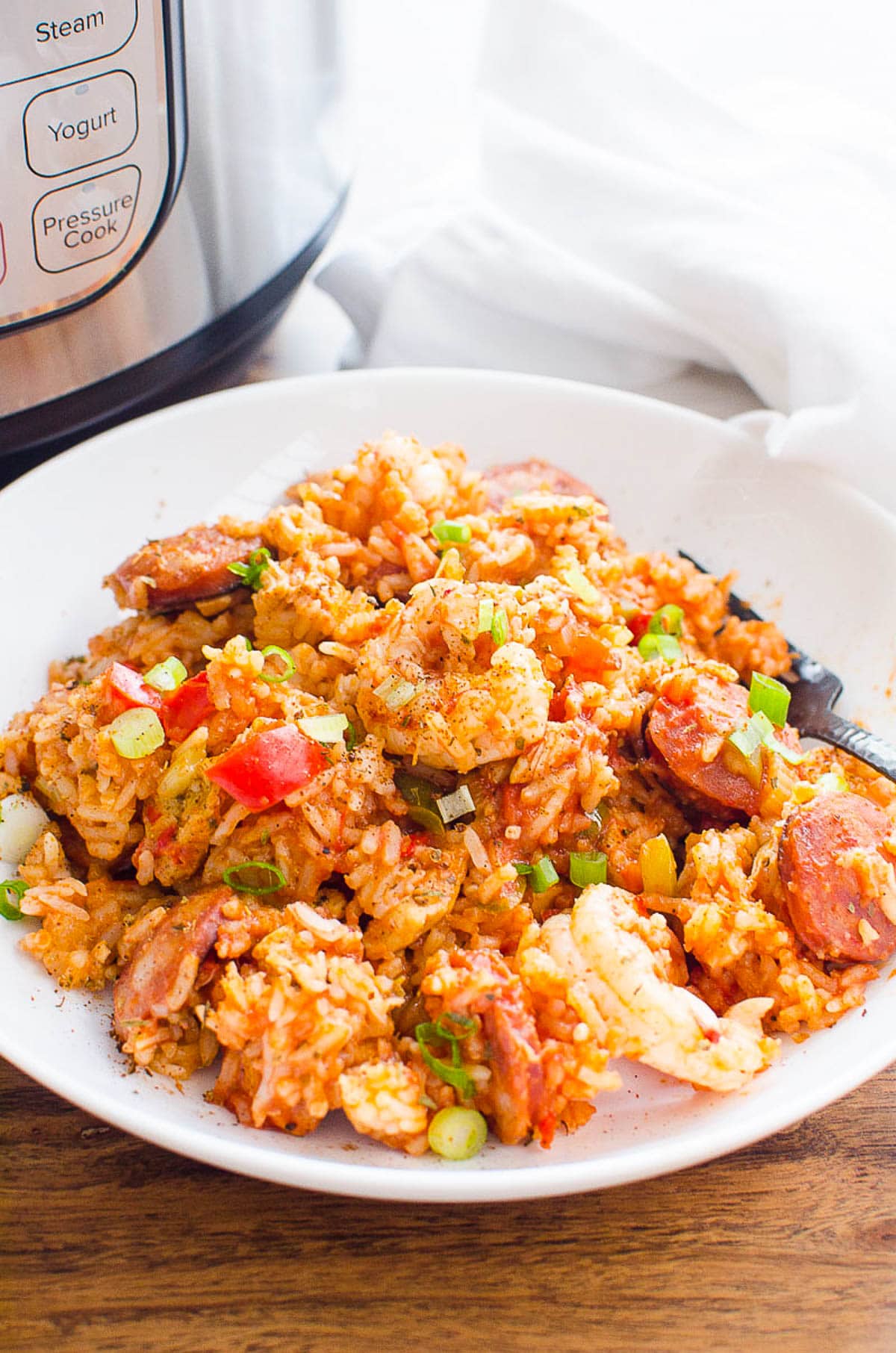 Instant pot Jambalaya garnished with green onion and served on white plate with a fork.