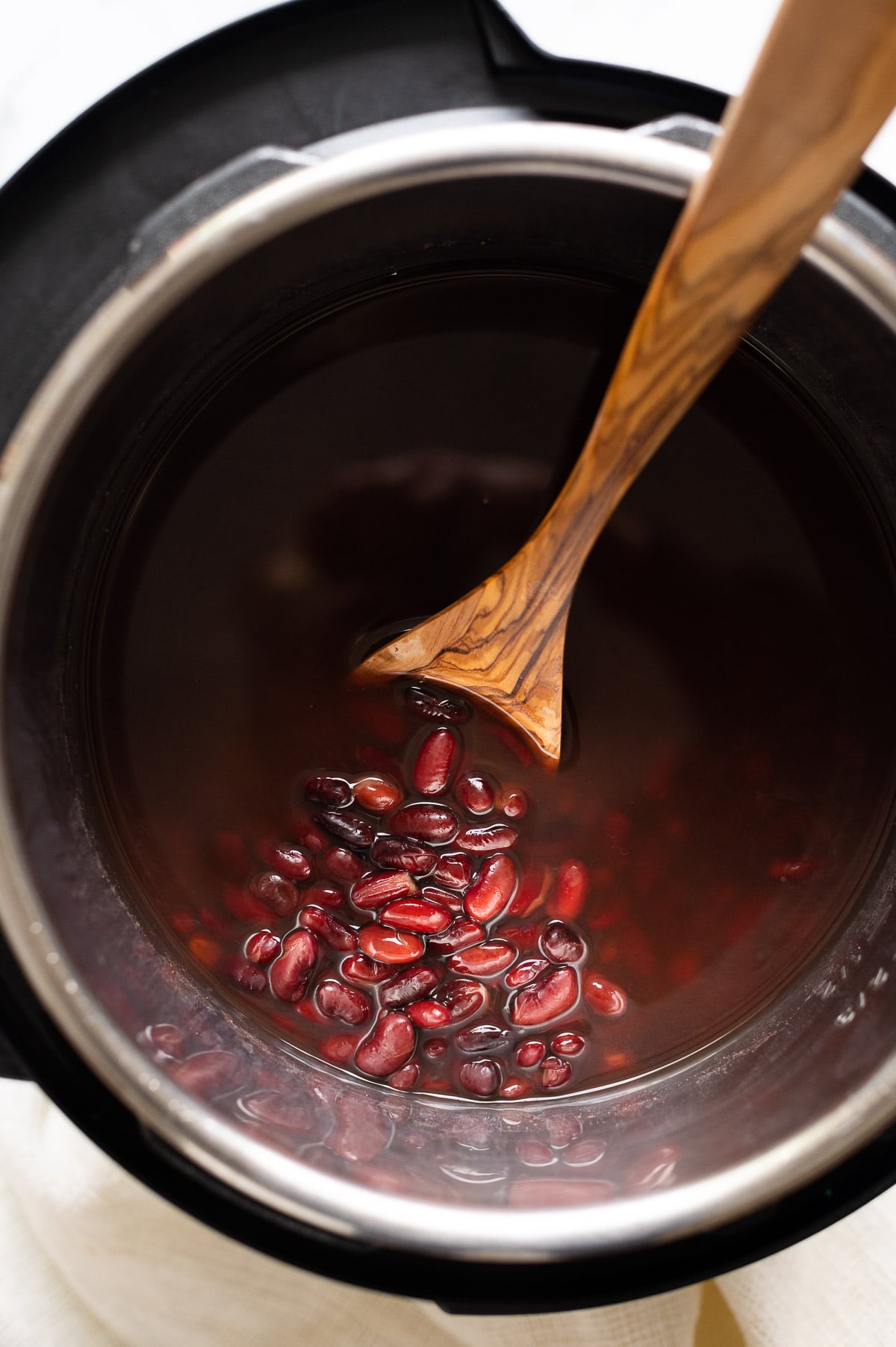 Kidney beans in cooking liquid in the instant pot pushed to the side with a spoon.