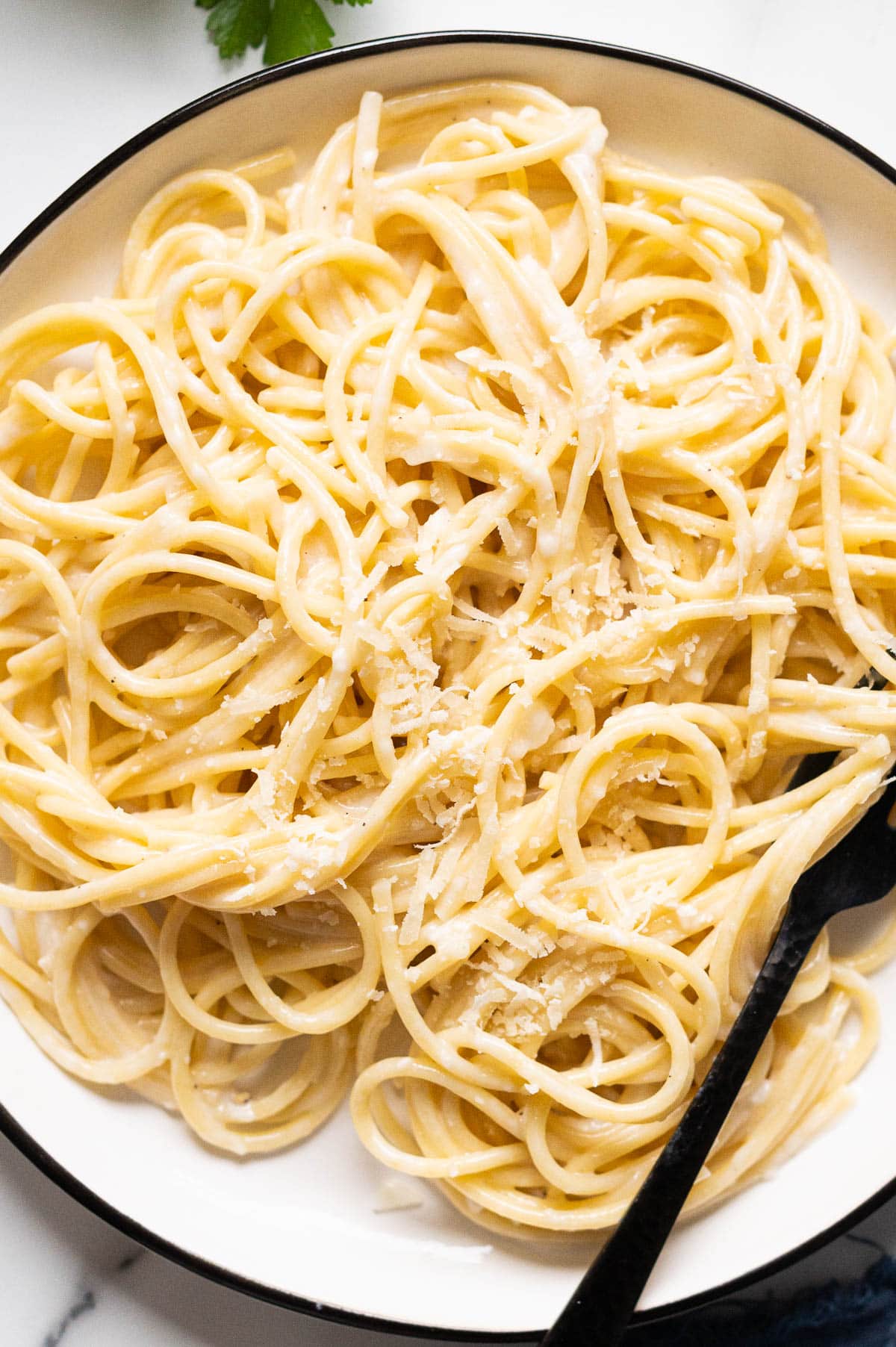 Spaghetti with healthier alfredo sauce and parmesan cheese on a plate.