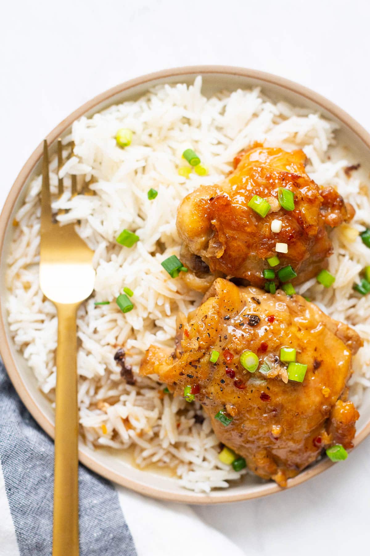 Slow cooker chicken thighs served with rice on a plate with golden fork. 