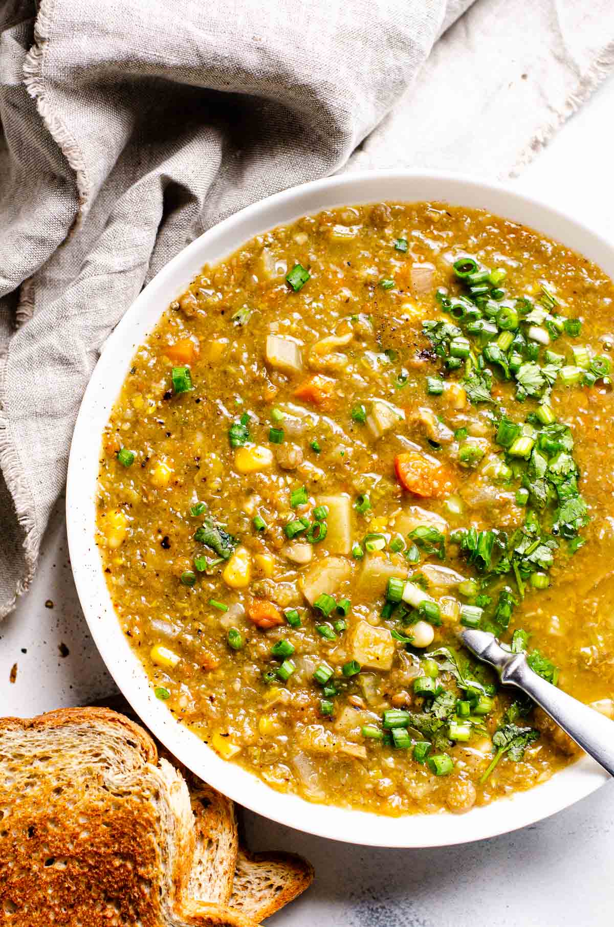 lentil soup made in crock pot in a bowl for serving with a gray linen and crusty brown bread