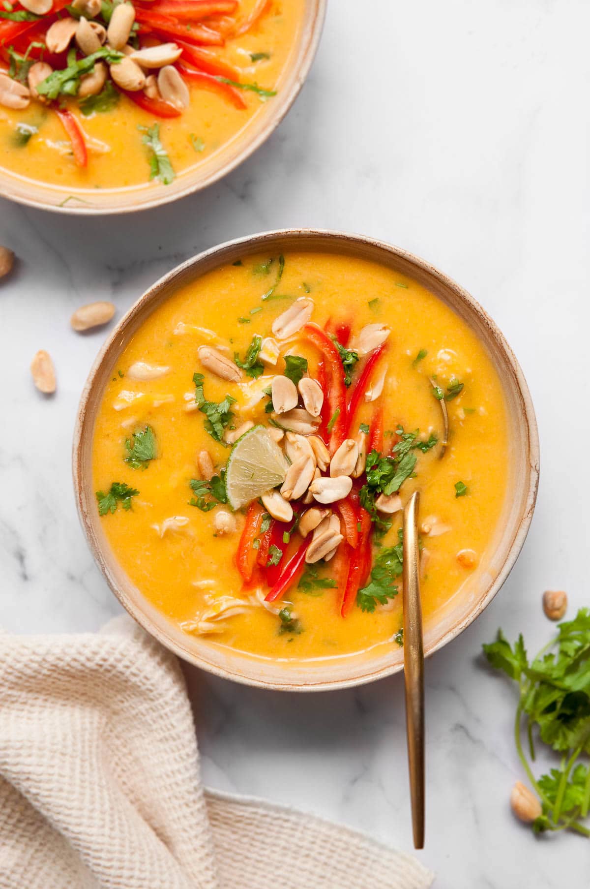 Thai chicken butternut squash with red pepper, peanuts and cilantro in a bowl.