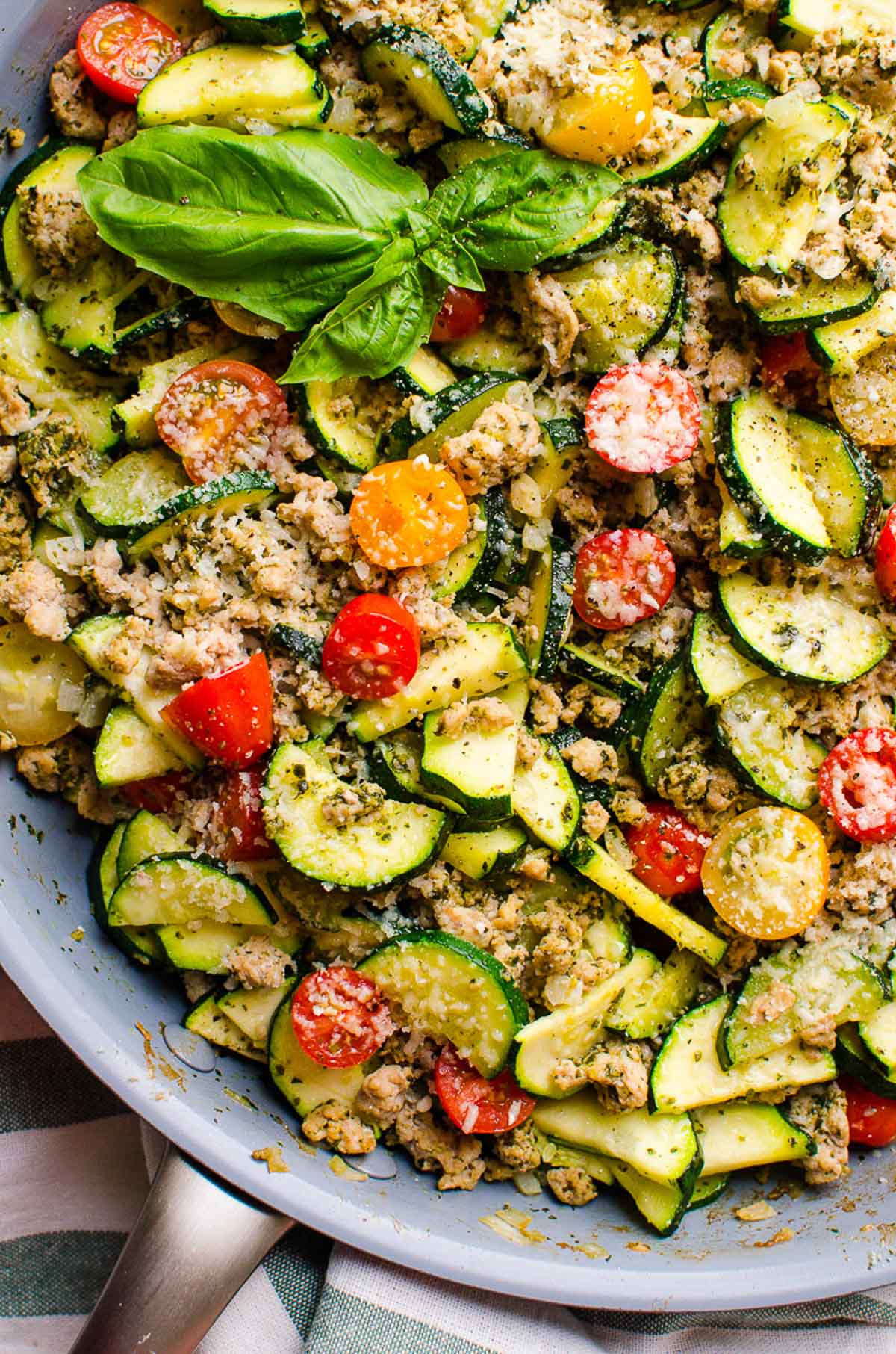 Low carb ground turkey and zucchini skillet with pesto and tomatoes in skillet.