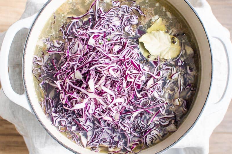 Shredded cabbage in pot with broth.